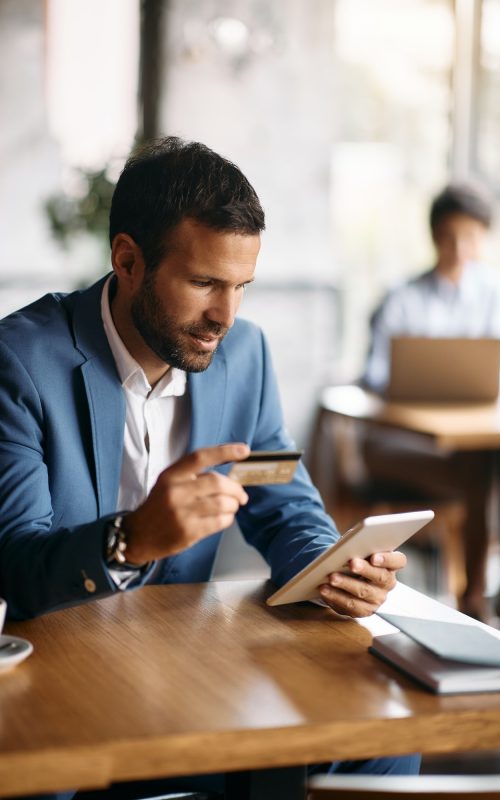 young-businessman-using-credit-card-and-digital-tablet-for-online-banking-in-a-cafe-.jpg